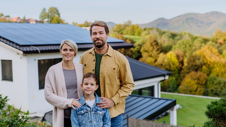 Happy family near their house with a solar panels. Alternative energy, saving resources and sustainable lifestyle concept.