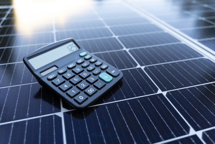 Image of a calculator on a solar panel representing the concept of saving energy with renewable energy